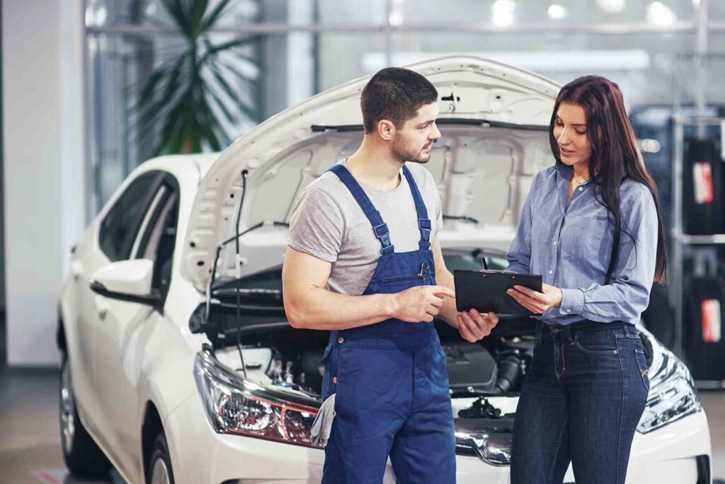 A man mechanic and woman customer discussing repairs done to her vehicle
